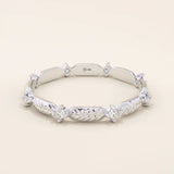 14k solid white gold ring with a repeating pattern of polished leaf shapes and bezel-set moissanites.
