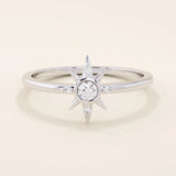 14k solid white gold starburst ring with a central round moissanite and smaller accent stones radiating along the points.
