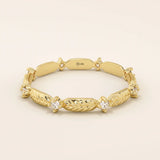 14k solid yellow gold band featuring alternating textured leaf motifs and round moissanite stones.
