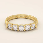 14k solid yellow gold band featuring five round brilliant cut moissanite stones in a classic prong setting with engraved detailing along the shank, timeless fine jewelry for weddings or anniversaries
