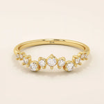 14k solid yellow gold band with alternating small and large round moissanite stones in a curved pavé setting.

