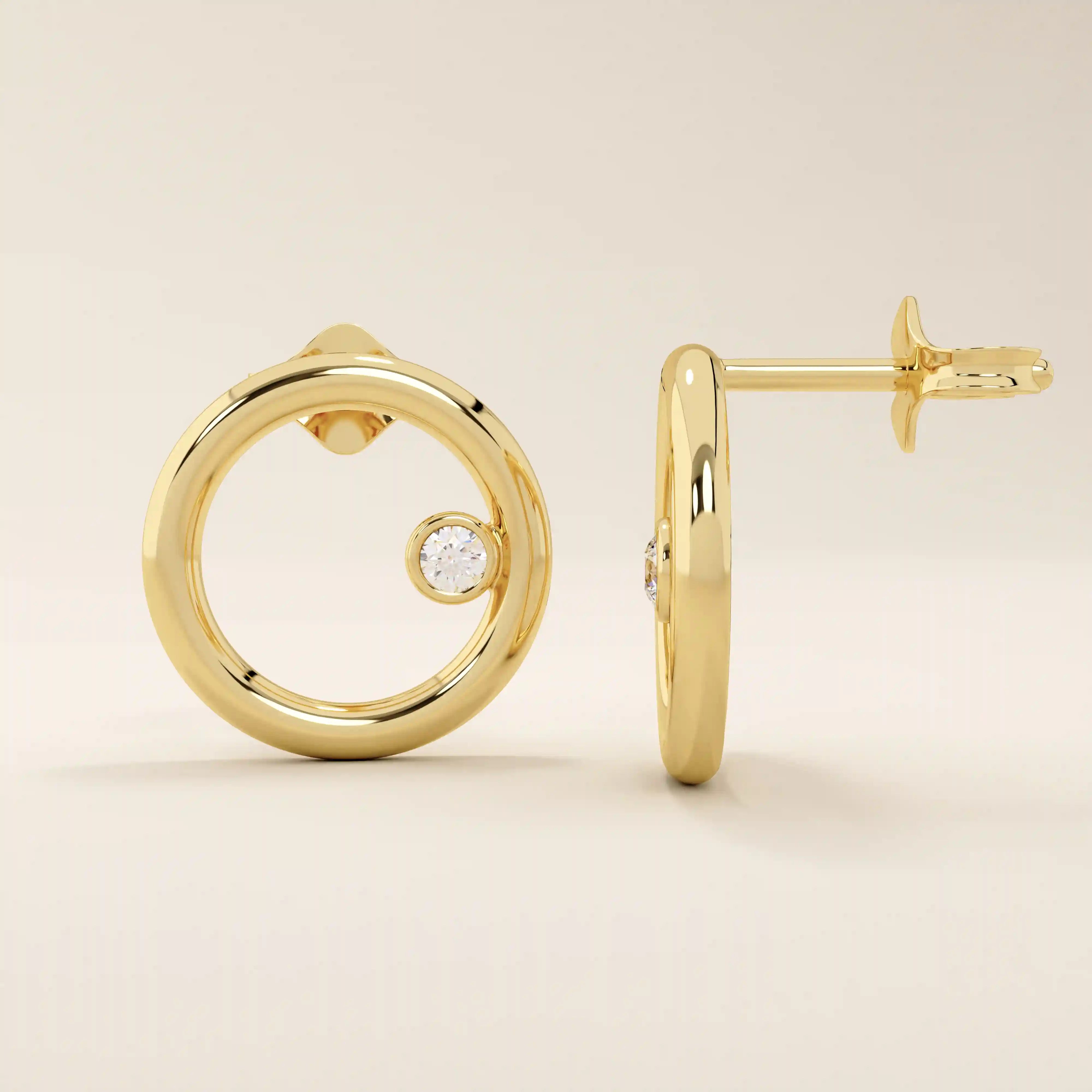 14k solid yellow gold circular karma stud earrings with a single bezel-set round moissanite floating at the inner edge of each hoop.
