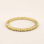 14k solid yellow gold slim wedding ring featuring a repeating marquise-shaped pattern around the band.
