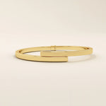 14k solid yellow gold wrap-around bangle bracelet featuring a sleek overlapping design with a polished finish.
