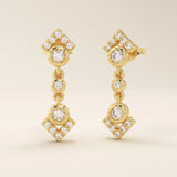 Angled view of 14k solid yellow gold dangling arrow studs, highlighting the linked bezel settings and pavé arrowhead ends.
