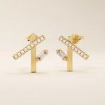 Angled view of 14k yellow gold asymmetrical bar stud earrings with pavé moissanite and a vertical baguette-cut stone detail.
