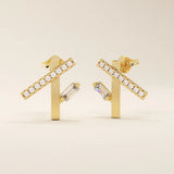 Angled view of 14k yellow gold asymmetrical bar stud earrings with pavé moissanite and a vertical baguette-cut stone detail.
