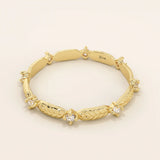 Angled view of a 14k yellow gold band showcasing alternating moissanite stones and polished leaf designs.
