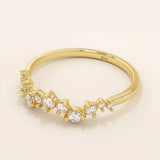 Angled view of a 14k yellow gold ring with alternating small and large moissanites in an elegant curved design.
