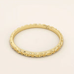 Angled view of a 14k yellow gold slim patterned wedding ring with repeating marquise shapes.
