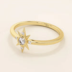 Angled view of a 14k yellow gold starburst ring, highlighting its radiant moissanite center and delicate side stones.
