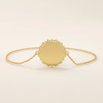 Angled view of a 14k yellow gold sun bracelet highlighting the detailed circular medallion with radiant edges on a dainty chain.
