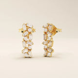 Baguette cluster stud earrings in 14k yellow gold featuring a mix of baguette and round stones in a scattered design.
