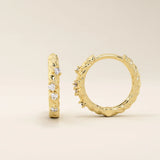 Close-up of 14k gold twist rope hoop earrings featuring moissanite stones along the braided design.
