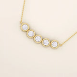 Close-up of 5 stone bezel necklace in polished 14k gold, highlighting the smooth circular settings and brilliant stones.
