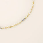 Close-up of a 14k gold bracelet with oval chain links and faceted mixed-metal bar accents for added shine.
