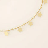 Close-up of a dangling star charm bracelet in gold, highlighting polished star shapes and bead accents on the chain.
