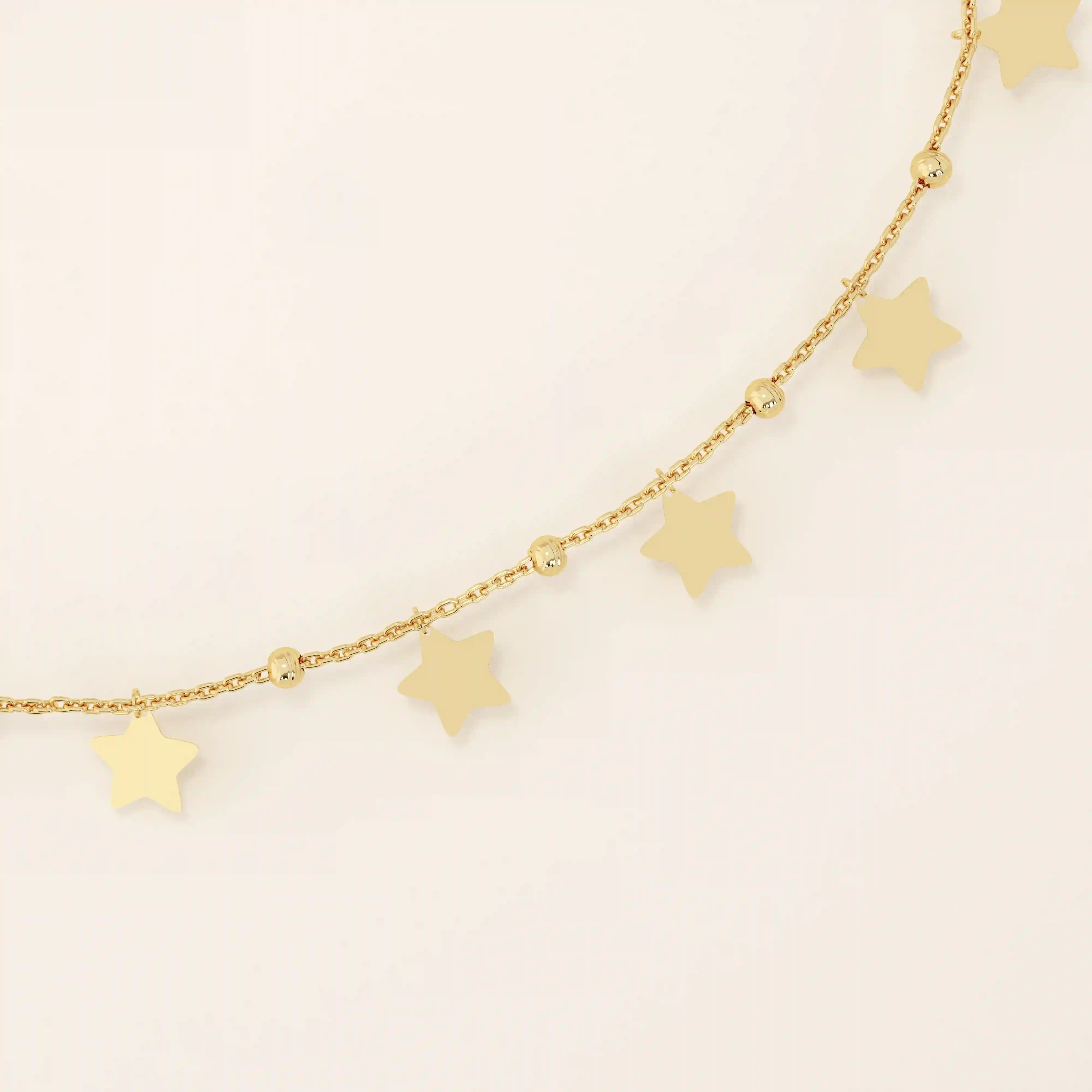 Close-up of a dangling star charm bracelet in gold, highlighting polished star shapes and bead accents on the chain.
