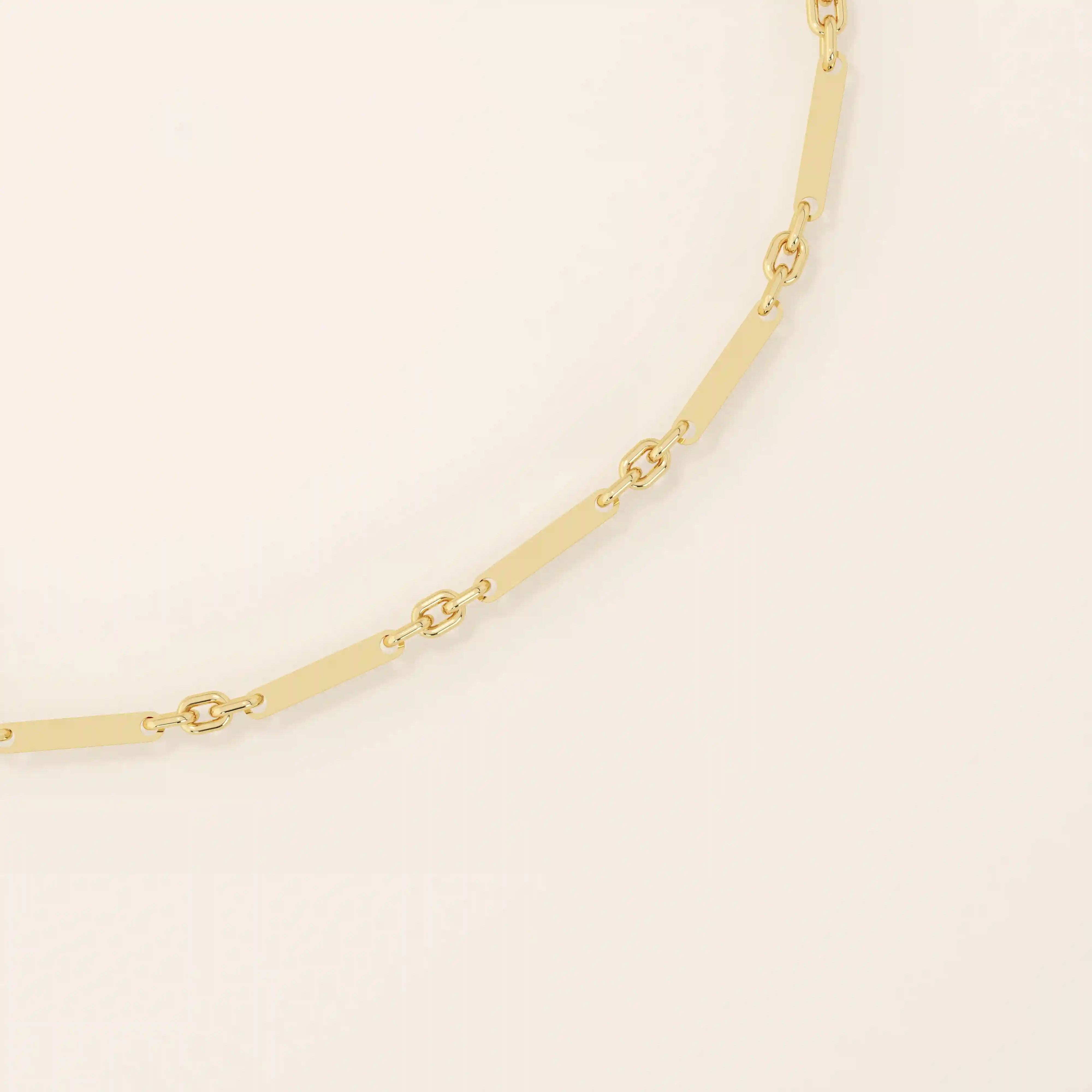 Close-up of a gold bracelet showing alternating flat bar links and small oval cable chain connectors.
