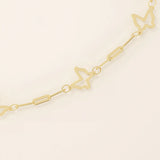 Close-up of a gold chain bracelet with butterfly-shaped cutout charms and fine elongated links.
