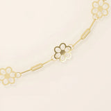 Close-up of a gold flower chain bracelet, highlighting the cut-out floral charms and polished linked design.
