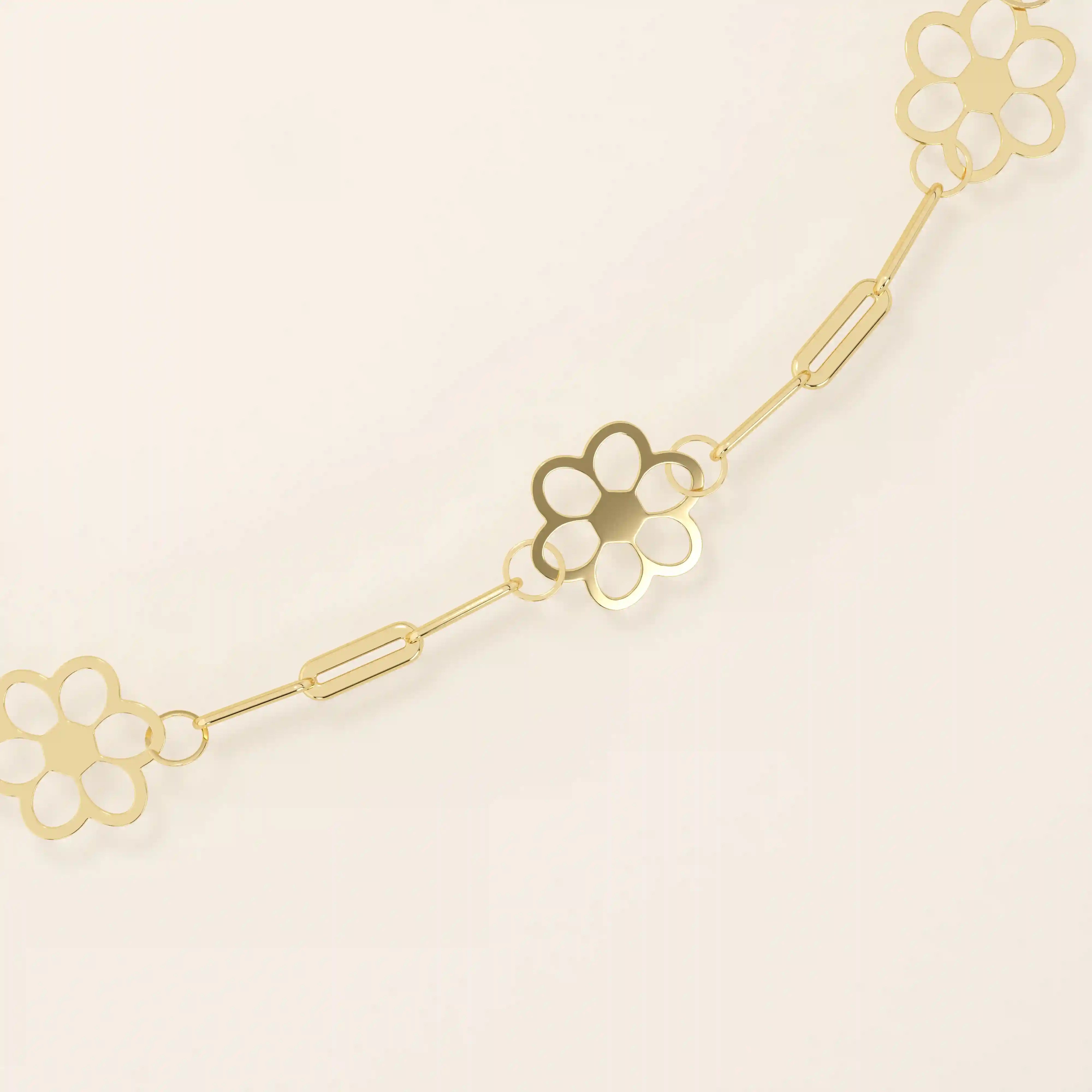 Close-up of a gold flower chain bracelet, highlighting the cut-out floral charms and polished linked design.
