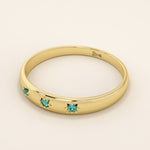 Close-up of a model’s hand wearing a 14k yellow gold dome ring with aquamarine gemstones in starburst settings across the band.