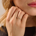 Close-up of a model’s hand wearing a 14k yellow gold pavé ring with alternating moissanite stone sizes.
