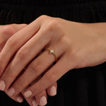 Close-up of a model’s hand wearing a 14k yellow gold starburst ring with moissanite center and accent stones.
