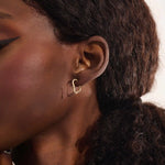 Close-up of a model wearing a 14k solid yellow gold abstract hoop stud earring with a modern sculptural design.

