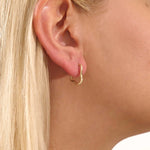 Close-up of a model wearing a 14k solid yellow gold abstract hoop stud earring with a modern sculptural design.

