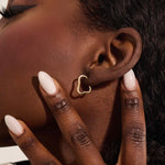 Close-up of a model wearing a 14k solid yellow gold abstract hoop stud earring with a modern sculptural design.
