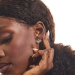 Close-up of a model wearing a 14k solid yellow gold fan stud earring, the moissanite stones catching the light for a glamorous, art deco-inspired look.

