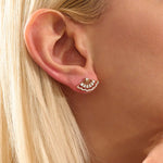 Close-up of a model wearing a 14k solid yellow gold fan stud earring, the moissanite stones catching the light for a glamorous, art deco-inspired look.

