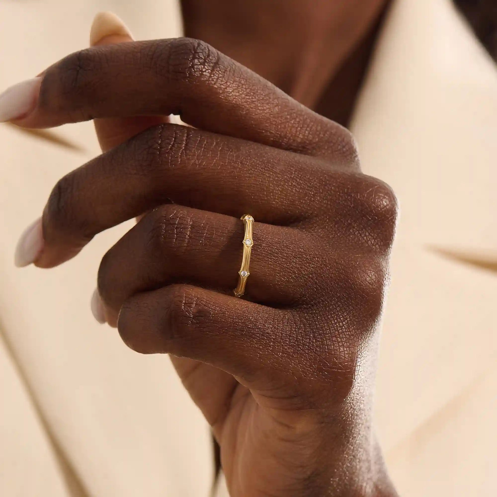 Close-up of a woman wearing a 14k solid yellow gold bamboo-inspired wedding band with evenly spaced moissanites
