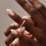 Close-up of a woman wearing a 14k solid yellow gold band with alternating baguette cut and round brilliant cut moissanite stones in a bezel setting, minimal and modern wedding or stacking ring
