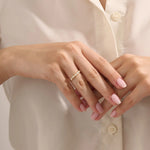 Close-up of a woman wearing a 14k solid yellow gold band with alternating baguette cut and round brilliant cut moissanite stones in a bezel setting, minimal and modern wedding or stacking ring
