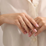 Close-up of a woman wearing a 14k solid yellow gold band with alternating baguette cut and round brilliant cut moissanite stones in a bezel setting, minimal and modern wedding or stacking ring
