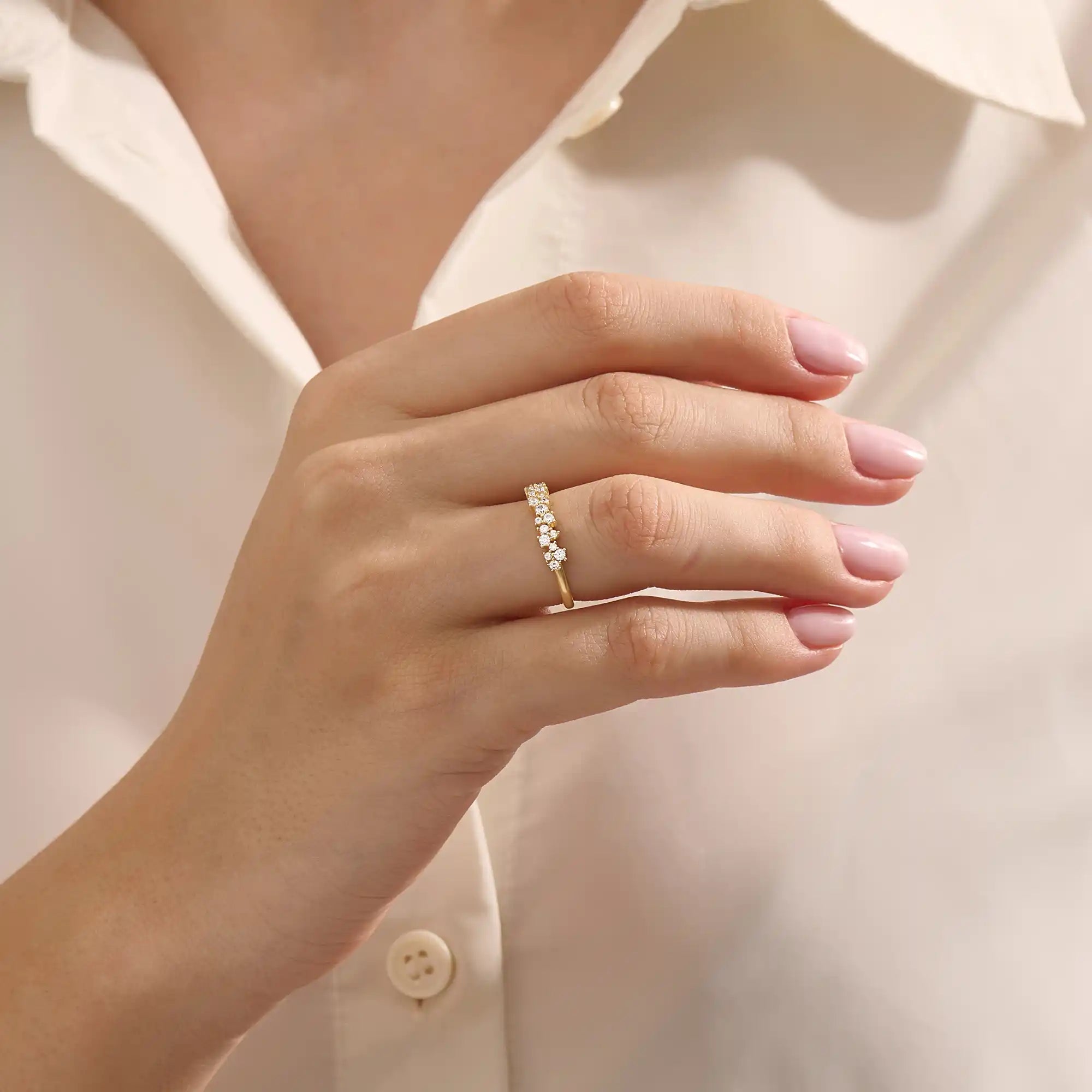Close-up of a woman wearing a 14k solid yellow gold band with clusters of round brilliant cut moissanite stones in prong settings, sparkling and sophisticated wedding or anniversary ring
