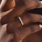 Close-up of a woman wearing a 14k solid yellow gold band with clusters of round brilliant cut moissanite stones in prong settings, sparkling and sophisticated wedding or anniversary ring
