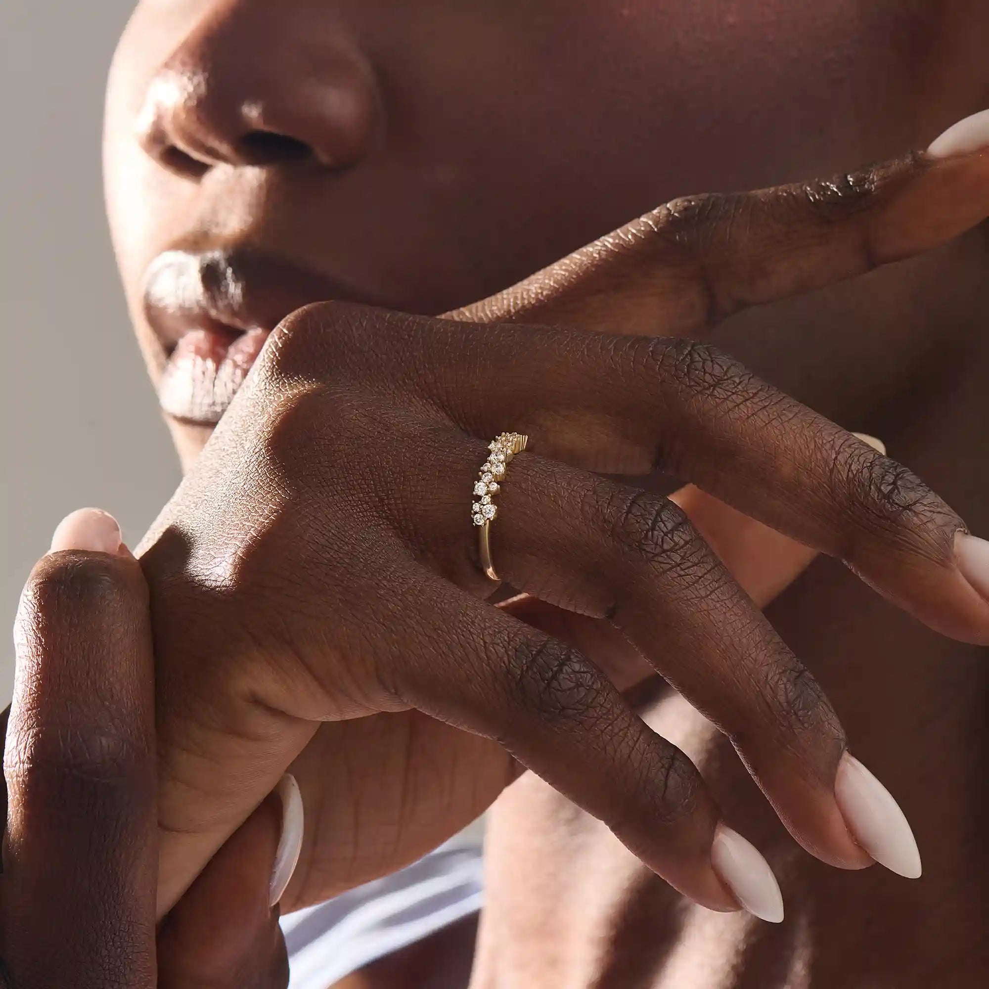 Close-up of a woman wearing a 14k solid yellow gold band with clusters of round brilliant cut moissanite stones in prong settings, sparkling and sophisticated wedding or anniversary ring
