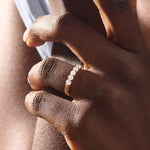 Close-up of a woman wearing a 14k solid yellow gold band with five round brilliant cut moissanite stones in a prong setting and engraved shank detail, sophisticated wedding or anniversary ring
