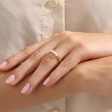 Close-up of a woman wearing a 14k solid yellow gold band with five round brilliant cut moissanite stones in a prong setting and engraved shank detail, sophisticated wedding or anniversary ring
