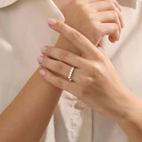 Close-up of a woman wearing a 14k solid yellow gold band with five round brilliant cut moissanite stones in a prong setting and engraved shank detail, sophisticated wedding or anniversary ring
