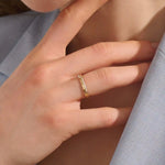 Close-up of a woman wearing a 14k solid yellow gold band with pointed chevron design and pavé set round brilliant cut moissanite stones, minimal and elegant wedding or stacking ring
