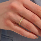 Close-up of a woman wearing a 14k solid yellow gold band with pointed chevron design and pavé set round brilliant cut moissanite stones, minimal and elegant wedding or stacking ring
