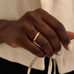 Close-up of a woman wearing a 14k solid yellow gold band with pointed chevron design and pavé set round brilliant cut moissanite stones, minimal and elegant wedding or stacking ring

