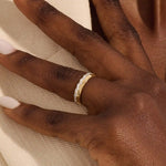Close-up of a woman wearing a 14k solid yellow gold band with round brilliant cut moissanite stones in a single row and polished bead accents, elegant and timeless wedding jewelry
