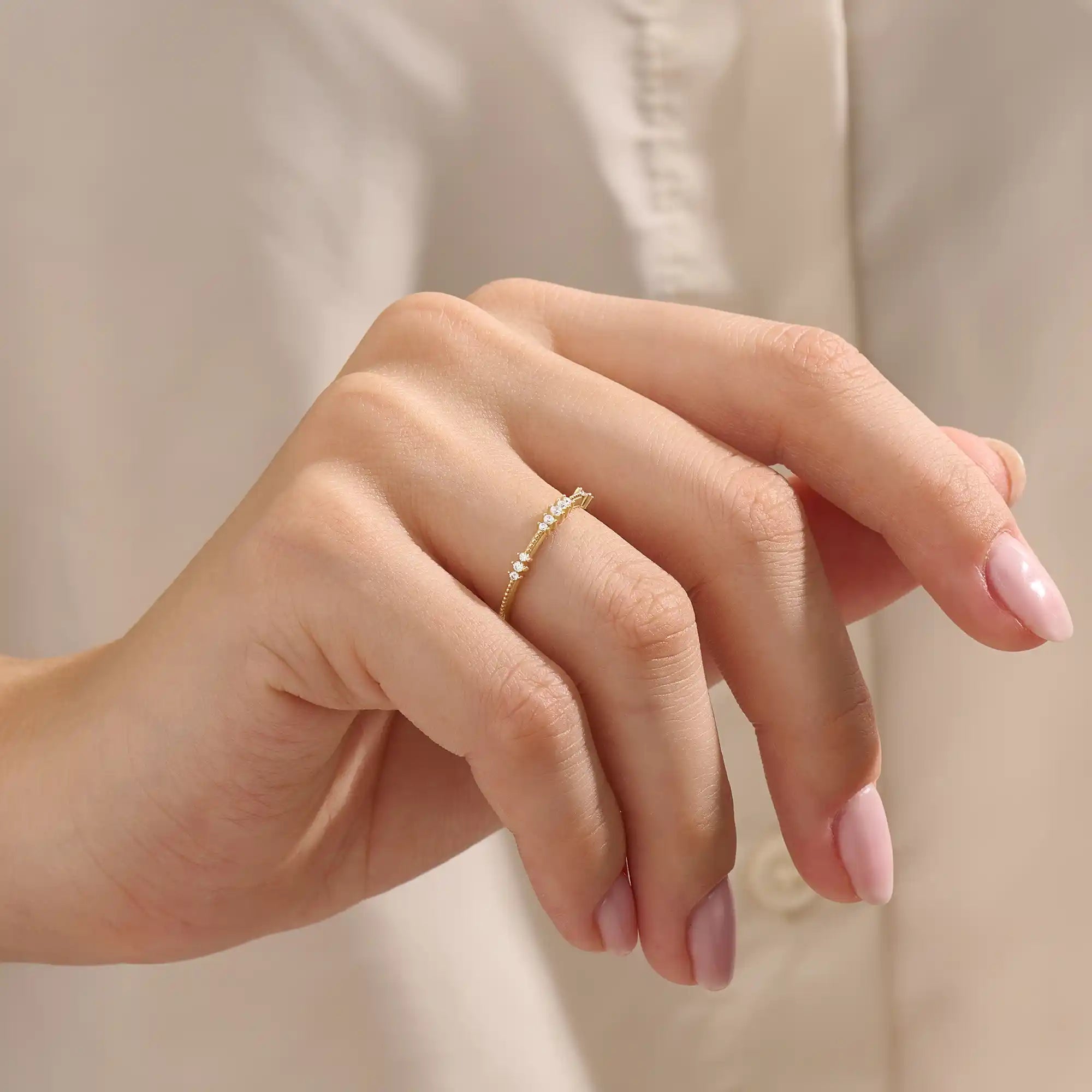 Close-up of a woman wearing a 14k solid yellow gold band with round brilliant cut moissanite stones in alternating prong and bead settings, minimal and elegant bridal jewelry
