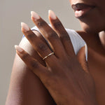 Close-up of a woman wearing a 14k solid yellow gold band with round brilliant cut moissanite stones in alternating prong and bead settings, minimal and elegant bridal jewelry
